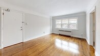 Located on the third floor at 126 St Paul Ave in Brantford, Ontario, this one-bedroom, one-bathroom unit offers a well-organized layout across a single floor. The living room is a bright, open space highlighted by warm hardwood flooring, neutral light-grey walls, and large windows that allow generous natural light to pour in. A radiator beneath the windows provides in-suite heating. The living room connects directly to the renovated kitchen, which features crisp white shaker-style cabinetry, white quartz countertops, a stainless steel double sink, a subway tile backsplash, and stainless steel appliances including a range, over-the-range microwave, dishwasher, and refrigerator. Light-toned tile flooring completes the kitchen's clean, modern aesthetic. The bedroom is a comfortable, well-proportioned room with the same warm hardwood floors, neutral walls, and access to closet space. The bathroom includes a full soaker tub and shower combination with white tile surround and chrome fixtures. A hallway connects the rooms, providing a practical flow throughout the unit. The overall ambiance is clean, bright, and move-in ready.