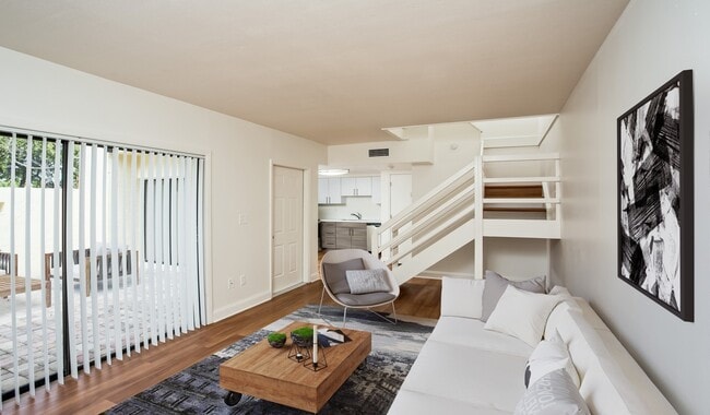 Spacious living room with access to private patio and wood flooring throughout - Four Quarters Apartments