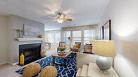 Located at 3209 Westbury Lake Dr in Charlotte, NC, this single-floor, 2-bedroom, 3-bathroom home offers a thoughtfully arranged layout ideal for comfortable everyday living. The living room serves as the heart of the home, featuring a ceiling fan, a fireplace, and multiple windows dressed with sheer curtains and blinds that fill the space with natural light. The open flow connects seamlessly to the dining area, which is bathed in light from a bank of windows, creating a warm and inviting atmosphere. The kitchen features warm wood cabinetry, granite-style countertops, a stainless steel sink, and a dishwasher, with hardwood-style flooring adding a polished finish. The primary bedroom is generously sized, highlighted by a curved bay window with a built-in bench seat — a charming architectural detail — along with plush carpeting and ample room for full-sized furnishings. The second bedroom is cozy and well-lit, with large windows and soft carpeting. The primary bathroom includes a long vanity with granite-style counters and hardwood-style flooring. A dedicated in-unit laundry room houses a full-sized washer and dryer. Two closets and a hallway round out this well-equipped, move-in-ready home.