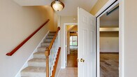 This three-floor home offers a thoughtfully designed layout with functional spaces spread across each level. The entry foyer features tile flooring and a carpeted staircase with a classic wood railing, white balusters, and a warm ceiling fixture, providing a welcoming transition between floors.

The kitchen is well-equipped with rich honey-toned cabinetry, granite countertops, and a full suite of stainless steel appliances, including an electric range, over-the-range microwave, and refrigerator. Light tile flooring runs throughout, and a sliding glass door opens directly onto a deck overlooking greenery, bringing natural light into the space.

Bedrooms are carpeted and finished in neutral tones, with some featuring vaulted ceilings and ceiling fans. Each bedroom includes a closet with double doors and wire shelving for organized storage, along with windows that allow natural light.

The primary bathroom includes a double-sink vanity with warm wood cabinetry, a soaking tub beneath an arched window, tile flooring, and built-in shelving. A secondary full bathroom offers a tub-shower combination, single vanity, and tile flooring.

The attached garage provides a concrete floor, automatic door with windows, and direct interior access, completing this practical and comfortable multi-floor home.