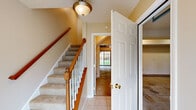 This three-floor home offers a thoughtfully designed layout with functional spaces spread across each level. The entry foyer features tile flooring and a carpeted staircase with a classic wood railing, white balusters, and a warm ceiling fixture, providing a welcoming transition between floors.

The kitchen is well-equipped with rich honey-toned cabinetry, granite countertops, and a full suite of stainless steel appliances, including an electric range, over-the-range microwave, and refrigerator. Light tile flooring runs throughout, and a sliding glass door opens directly onto a deck overlooking greenery, bringing natural light into the space.

Bedrooms are carpeted and finished in neutral tones, with some featuring vaulted ceilings and ceiling fans. Each bedroom includes a closet with double doors and wire shelving for organized storage, along with windows that allow natural light.

The primary bathroom includes a double-sink vanity with warm wood cabinetry, a soaking tub beneath an arched window, tile flooring, and built-in shelving. A secondary full bathroom offers a tub-shower combination, single vanity, and tile flooring.

The attached garage provides a concrete floor, automatic door with windows, and direct interior access, completing this practical and comfortable multi-floor home.
