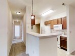 This single-floor unit in Knoxville, Tennessee offers a well-organized layout designed for comfortable everyday living. The open living area is anchored by soft carpet flooring and a ceiling fan with integrated lighting, creating a relaxed and airy atmosphere. French doors allow natural light to pour in, and a pass-through counter connects the living space seamlessly to the kitchen.

The galley-style kitchen is a functional highlight, featuring warm-toned wood cabinetry lining both walls, light countertops, a double-basin stainless steel sink, and white appliances including a range, built-in microwave, refrigerator, and dishwasher. Pendant lighting adds a touch of character, while durable wood-look flooring runs throughout the kitchen and hallway areas.

A central hallway connects the bedrooms, each finished with plush carpet and ceiling fans. The bedrooms are bright and generously proportioned, with at least one featuring a large window that invites natural light. The unit includes two bathrooms: one with a vanity and wood cabinetry, and another full bath complete with a tub-shower combination, single vanity, and a large mirror. Wood-look flooring carries through the bathrooms, maintaining a cohesive aesthetic across the entire space.