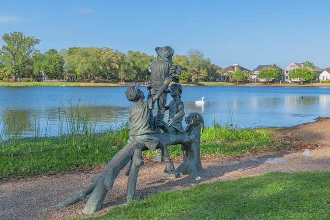 This art structure of kids sitting along the water is seen in Daniel Island's Smythe Park.