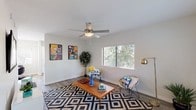 This single-story residence in Mesa, Arizona offers a well-designed layout that balances comfort and functionality throughout. The living room serves as a welcoming centerpiece, featuring wood-style flooring, a ceiling fan with light fixture, and a large window that frames lush outdoor greenery, filling the space with natural light. The kitchen has been thoughtfully updated with crisp white shaker cabinetry, grey countertops, classic white subway tile backsplash, and a full suite of stainless steel appliances including a dishwasher, range, and built-in microwave. A window above the sink further brightens this space. The dining area connects seamlessly to the outdoors via a sliding glass door framed by vertical blinds, creating an inviting indoor-outdoor flow. The bedrooms are carpeted and generously proportioned, each with windows that allow ample natural light. Several bedrooms include closets, including one with a sliding closet door. The bathrooms are finished with grey countertops, white cabinetry, large vanity mirrors, and modern lighting. One bathroom features a tub-shower combination with tiled surround. The home's neutral color palette and consistent finishes create a cohesive, move-in-ready atmosphere throughout.