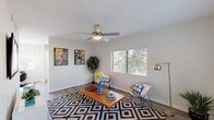 This single-story residence in Mesa, Arizona offers a well-designed layout that balances comfort and functionality throughout. The living room serves as a welcoming centerpiece, featuring wood-style flooring, a ceiling fan with light fixture, and a large window that frames lush outdoor greenery, filling the space with natural light. The kitchen has been thoughtfully updated with crisp white shaker cabinetry, grey countertops, classic white subway tile backsplash, and a full suite of stainless steel appliances including a dishwasher, range, and built-in microwave. A window above the sink further brightens this space. The dining area connects seamlessly to the outdoors via a sliding glass door framed by vertical blinds, creating an inviting indoor-outdoor flow. The bedrooms are carpeted and generously proportioned, each with windows that allow ample natural light. Several bedrooms include closets, including one with a sliding closet door. The bathrooms are finished with grey countertops, white cabinetry, large vanity mirrors, and modern lighting. One bathroom features a tub-shower combination with tiled surround. The home's neutral color palette and consistent finishes create a cohesive, move-in-ready atmosphere throughout.