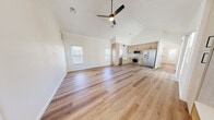 Located in Albuquerque, NM, this thoughtfully designed 2-bedroom, 2-bathroom single-story home offers a clean, modern aesthetic with high-quality finishes throughout. The open-concept living and kitchen area is anchored by soaring vaulted ceilings and a ceiling fan, creating an airy, expansive feel. Warm-toned luxury vinyl plank flooring runs seamlessly throughout the entire home, complementing the bright white walls and abundant natural light from multiple windows. A built-in entry nook with storage cabinetry provides a functional and stylish welcome near the front door.

The kitchen is a standout, featuring light wood flat-panel cabinetry with matte black hardware, a deep farmhouse sink, white quartz countertops, subway tile backsplash, and a full suite of stainless steel appliances including a gas range, over-the-range microwave, dishwasher, and French door refrigerator. Both bedrooms are generously proportioned, well-lit by multiple windows, and include ceiling fans. The primary bedroom offers a spacious walk-in closet with built-in shelving and hanging rods. A second closet with ample shelving provides additional storage. The bathrooms are elegantly finished, with one featuring a light wood vanity with quartz countertops, matte black fixtures, and a tub/shower combo clad in striking green glazed tile.