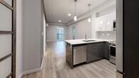 Located at 711 Treanor Avenue in Langford, BC, this thoughtfully designed 2-bedroom, 1-bathroom unit offers a modern aesthetic throughout its efficiently planned single-floor layout. The open-concept living area seamlessly integrates the kitchen, dining, and living spaces, all finished with light wood-look flooring that enhances the bright, airy atmosphere. The contemporary kitchen is a standout feature, showcasing two-tone cabinetry with dark lower and white upper cabinets, a crisp white quartz peninsula with bar seating, stainless steel appliances including a dishwasher, and stylish pendant lighting overhead. A tiled backsplash and ample upper cabinet storage add both function and style. The living area extends toward a balcony, inviting natural light deep into the space. The two bedrooms are carpeted for comfort, each featuring distinctive sliding closet doors with dark wood frames and frosted glass panels — a striking design detail. The full bathroom is finished in a clean, minimalist style with neutral tile flooring, a white vanity, and a full soaker tub with shower. A dedicated in-unit laundry area with wire shelving adds everyday convenience. Two closets provide additional storage throughout the unit.