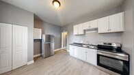 Located at 437 W Bancroft Street in Toledo, Ohio, this one-bedroom, one-bathroom unit offers a well-organized layout across a single floor. Consistent light wood-style flooring and neutral gray wall tones flow throughout the space, creating a cohesive and clean aesthetic.

The kitchen is a functional highlight, featuring white shaker-style cabinetry — both upper and lower — paired with dark countertops and a stainless steel sink. Stainless steel appliances, including a freestanding electric range and a full-size refrigerator, complete the kitchen. A window adjacent to the kitchen allows natural light to fill the space.

The bedroom is comfortably proportioned, featuring tall windows with blinds that bring in ample natural light and offer views of the surrounding neighborhood. Crisp white trim and baseboards contrast attractively against the gray walls, and a closet provides practical storage.

The bathroom is clean and straightforward, equipped with a full-size soaking tub and shower surround, a white vanity with sink, a mirrored medicine cabinet, and overhead lighting. The same light flooring carries through from the main living areas.

Two hallways connect the rooms efficiently, and a staircase provides access to the unit. Overall, the space presents a tidy, move-in-ready environment with updated finishes throughout.