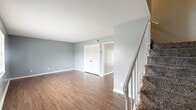 Located at 2103 Nottingham Way in Albany, Georgia, this two-story home offers three bedrooms and three bathrooms across a thoughtfully arranged floor plan. The main level features two living areas and a dedicated dining room, all finished with warm wood-look flooring and soft gray walls accented by crisp white trim. A carpeted staircase with a white railing connects the floors, and large windows throughout the main level invite natural light and outdoor views. The kitchen is equipped with white cabinetry, light countertops, a black electric range, a dishwasher, and a double sink beneath a window — offering both functionality and brightness. The dining area features classic chair-rail molding detail, adding a traditional touch to the space. Upstairs, the bedrooms are finished with plush carpet and ceiling fans, providing comfort and practicality. The generously sized primary bedroom offers ample space and natural light. The bathrooms include tiled tub-shower combinations with clean, classic white finishes. Closets on both floors provide useful storage throughout. Textured ceilings and consistent cool-gray wall tones give the entire home a cohesive, neutral aesthetic well-suited for a variety of furnishing styles.