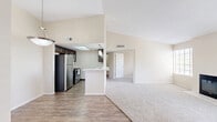 Located at 1050 S Bill Martin Dr in Tucson, Arizona, this two-bedroom, one-bathroom single-story residence offers a well-organized layout across a comfortable footprint. The living room serves as the heart of the home, featuring soaring vaulted ceilings, plush carpeting, and a classic fireplace framed by a tiled hearth. Large windows fitted with plantation-style blinds invite abundant natural light, while a sliding glass door opens to a private balcony with open outdoor views — a standout feature of the space. The kitchen is outfitted with rich dark-stained cabinetry, light stone countertops, and stainless steel appliances including a full-size refrigerator, range, and dishwasher. A skylight above adds a bright, airy quality to the cooking area. Wood-look flooring runs through the kitchen, entrance, hallway, and bathroom, providing a cohesive and durable finish. The bathroom features a dark wood vanity with a framed mirror, stone-topped counters, and modern lighting. Both bedrooms are carpeted and filled with natural light from windows, offering a calm and restful atmosphere. A dedicated closet and entrance round out the thoughtful floor plan, making this a functional and inviting Tucson residence.