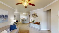 This single-floor residence is thoughtfully designed with an open-concept layout that seamlessly connects the living, dining, and kitchen areas. The living room is finished with plush carpeting, crown molding, and a ceiling fan with light fixture, lending a comfortable and polished feel. Sliding glass doors lead to a private balcony, allowing natural light to fill the space and providing outdoor views. A separate seating nook is defined by a decorative beam, adding subtle architectural character.

The kitchen features white cabinetry, white appliances, and a peninsula with bar seating, making it both functional and accessible to the main living area. Tile flooring extends through the entry and kitchen, transitioning to carpet in the living and sleeping areas.

Both bedrooms are generously proportioned, each equipped with a ceiling fan, a window that invites natural light, and closet access. The primary bathroom includes a wide vanity with ample counter space, a large mirror, and a tub-shower combination with tile surround. A second full bathroom also features a tub-shower combination and tile flooring.

A dedicated in-unit laundry closet houses a full-size washer and dryer with overhead shelving, adding everyday convenience to this well-appointed residence.