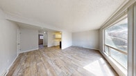 Located at 15110 Macadam Rd S in Tukwila, WA, this single-floor residence offers a practical and efficient layout with two bedrooms, one bathroom, and a combined kitchen and living area. The open living room is bright and welcoming, featuring light wood-look flooring, neutral gray walls, a textured ceiling, and a large picture window that fills the space with natural light. The galley-style kitchen is well-appointed with white cabinetry, light countertops, a single-basin sink, and includes appliances such as an electric range and refrigerator, all complemented by matching wood-look flooring. Both bedrooms feature plush carpeting, neutral tones, and textured ceilings. The primary bedroom offers a comfortable, generously sized layout with a sliding-door closet, while the second bedroom also includes a closet and a window with blinds for natural light and privacy. Baseboard heating is present throughout the home. The full bathroom includes a shower/tub combo with grab bars, a vanity with under-sink storage, and wood-look tile flooring. A hallway connects the main living areas to the bedrooms and bathroom, contributing to a straightforward and functional flow throughout the home.