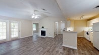 Located at 2300 Country Walk in Snellville, Georgia, this 2-bedroom, 1-bathroom single-floor unit offers a well-designed layout with a blend of comfort and functionality. The entryway opens onto rich hardwood-style flooring that extends throughout the main living areas, setting a warm and inviting tone.

The spacious living room is a standout feature, highlighted by vaulted ceilings, a ceiling fan with light fixture, and a classic wood-burning fireplace with a white-painted surround and tile hearth. French doors along one wall invite natural light and provide outdoor access, enhancing the open feel of the room.

The galley-style kitchen is efficiently laid out with white cabinetry, ample upper and lower storage, track lighting, a double-basin sink, and white appliances including a range and refrigerator. A breakfast bar with pendant lighting connects the kitchen to the living area, ideal for casual dining.

Both bedrooms are carpeted for comfort and offer closet space and windows that allow natural light. The full bathroom features a wide vanity with white cabinetry, a large mirror, recessed lighting, a tub/shower combination, and hardwood-style flooring. The textured ceilings throughout add a subtle architectural detail to each room.