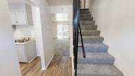 Located at 828 Westway Street in Elizabeth City, NC, this two-story home offers a practical and well-organized layout spread across two floors. The main level features durable hardwood-style flooring throughout the entryway and kitchen, with a bright living room carpeted for comfort and fitted with large vertical blinds that invite natural light. The kitchen includes a window with exterior views, providing a pleasant and functional cooking space. A carpeted staircase with black metal railings connects the two floors, adding a clean, modern touch to the interior. Upstairs, both bedrooms are carpeted and filled with natural light from individual windows overlooking the outdoors. The primary bedroom is a generously sized retreat featuring an expansive wall of louvered bi-fold closet doors, offering excellent storage capacity. The second bedroom is cozy and well-proportioned, with its own closet access. The shared full bathroom is bright and clean, finished with hardwood-style flooring, a white vanity, and a full tub-shower combination. Additional closets are distributed across both floors, maximizing storage. With a neutral color palette of crisp whites and soft grays throughout, the home presents a clean and move-in-ready ambiance.