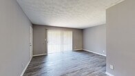 Located at 1231 Clairmont Rd in Decatur, GA, this single-story 2-bedroom, 1-bathroom home offers a functional and comfortable layout with consistent neutral-toned finishes throughout. The living room is anchored by durable hardwood-style flooring and features large sliding glass doors fitted with vertical blinds, allowing ample natural light to fill the space. A second windowed room with matching flooring provides additional flexible living or dining space. The kitchen is well-appointed with gray shaker-style cabinetry, marble-look countertops and backsplash, a double stainless steel sink, and a stainless steel dishwasher, all illuminated by a bright window. Both bedrooms are finished with plush carpeting and ceiling fans with light fixtures, creating a comfortable and quiet retreat. The spacious primary bedroom features two closets, offering generous storage. The secondary bedroom also benefits from natural light via a large window. The full bathroom includes a tiled tub-shower combination with sliding glass doors, white tile walls, and hardwood-style flooring. A hallway connects the main living areas to the bedrooms, and a walk-in closet provides additional storage. The home's cohesive gray color palette and clean finishes lend a modern, move-in-ready appeal.