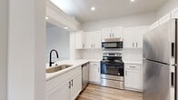 Located at 200 Kellington Dr N in Houston, TX, this single-story, 3-bedroom, 2-bathroom home offers a clean, modern aesthetic throughout. The open-concept layout connects the living room, dining area, and kitchen seamlessly, with light wood-look flooring flowing across the main living spaces. The living room features crown molding and a ceiling fan, with large windows allowing ample natural light and views of the outdoors. The dining area is accented by crown molding, wainscoting, and a striking black pendant light. The kitchen is well-equipped with white shaker cabinetry, black hardware, white countertops, stainless steel appliances including a range, over-the-range microwave, dishwasher, and refrigerator, and a single-basin sink with a matte black faucet. A hallway connects the bedrooms and bathrooms, where plush carpet flooring adds warmth. The spacious primary bedroom includes closet access. The bathrooms feature white vanities with black fixtures and a tub-shower combination. A dedicated laundry room with washer and dryer hookups rounds out the home's practical amenities, making this a comfortable and functional Houston residence.