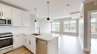 Located at 445 South Ave E in Westfield, NJ, this well-appointed 2-bedroom, 2-bathroom residence offers a thoughtfully designed single-floor layout with generous living space throughout. The open-concept kitchen, dining, and living area serves as the heart of the home, featuring light hardwood-style flooring, large windows that invite abundant natural light, and views of the surrounding area. The kitchen is outfitted with crisp white shaker cabinets, quartz countertops, a central island with an undermount sink, stainless steel appliances including a gas range, dishwasher, microwave, and refrigerator, and stylish gold pendant lighting. The living area flows seamlessly from the kitchen and connects to a private balcony. Both bedrooms are well-sized, with the primary bedroom offering notable square footage, light-toned walls, and access to ample closet storage via built-in shelving and hanging rods across three closets. The two bathrooms are distinctly finished — one features marble-look tile, a soaking tub, and a white vanity, while the other includes a double-sink vanity with dark countertops and tile flooring. Neutral warm-gray paint tones, recessed lighting, and white panel doors complete the clean, modern aesthetic throughout.