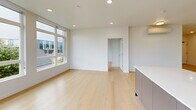 Located at 3956 N Vancouver Ave in Portland, Oregon, this thoughtfully designed two-bedroom, one-bathroom unit offers a clean, contemporary aesthetic throughout its well-utilized single-floor layout. Light hardwood flooring flows seamlessly from room to room, complementing the bright white walls and recessed lighting that give the space an airy, modern feel.

The open-concept kitchen and living area serves as the heart of the unit. The kitchen is outfitted with dark cabinetry, stainless steel appliances including a refrigerator, microwave, and range, a large central island with a white countertop and undermount sink, and tall clerestory windows that draw in abundant natural light. The living area extends generously from the kitchen, featuring oversized windows with neighborhood views and a wall-mounted mini-split system for climate control.

Both bedrooms are bright and well-proportioned, with large windows overlooking the surrounding greenery and streetscape. The primary bedroom includes a dedicated closet, and the unit offers a total of three closets providing ample storage. An in-unit laundry area adds everyday convenience.

The full bathroom features large-format tile flooring, a sleek floating vanity with white countertops and a backlit mirror, and a separate glass-enclosed walk-in shower with subway tile walls and mosaic tile flooring. A hallway connects the private areas of the unit with ease and efficiency.