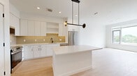 This thoughtfully designed one-bedroom, one-bathroom residence in Revere, MA offers a clean, contemporary aesthetic throughout. Light hardwood flooring flows seamlessly across the entire unit, creating a cohesive and airy feel from room to room.

The open-concept kitchen and living area serves as the heart of the home. The kitchen is outfitted with flat-front white cabinetry extending to the ceiling, a warm sage-toned subway tile backsplash, stainless steel appliances including a range, microwave, and refrigerator, and a striking white waterfall-edge island. A modern pendant light fixture anchors the space above the island, adding a designer touch.

The bedroom is bright and serene, featuring large windows that frame open outdoor views of the surrounding Revere landscape, allowing natural light to fill the room throughout the day. The clean white walls and light flooring contribute to a calm, minimalist atmosphere.

The bathroom maintains the unit's modern palette with light flooring, white walls, and a clean, functional layout that includes a bathtub with shower and essential fixtures. A hallway connects the rooms efficiently, completing the unit's well-organized floor plan. Overall, this residence combines modern finishes with practical design for comfortable urban living.