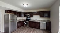 Located at 6475 Recknore Dr in Milford, Delaware, this three-floor residence offers a well-appointed layout designed for comfortable everyday living. The kitchen serves as a functional centerpiece, showcasing rich dark espresso cabinetry with raised-panel detailing, granite-look countertops, and a full suite of stainless steel appliances including a refrigerator, electric range, over-the-range microwave, and dishwasher. Wood-look plank flooring runs throughout the kitchen, adding warmth and durability to the space.

The bedrooms are generously sized, each featuring plush wall-to-wall carpeting, ceiling fans with integrated lighting, and windows dressed with horizontal blinds that allow natural light to filter in. The multi-floor layout provides a sense of separation between living and sleeping areas.

The bathrooms are clean and efficiently designed. One features a full soaking tub and shower combination with a dark vanity, while another offers a standalone glass-door shower with wood-look flooring and a bright window. A dedicated in-unit laundry area accommodates a full-size washer and dryer side by side, with overhead shelving for additional storage. Overall, the residence presents a practical and cohesive interior throughout all three levels.