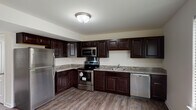 Located at 6475 Recknore Dr in Milford, Delaware, this three-floor residence offers a well-appointed layout designed for comfortable everyday living. The kitchen serves as a functional centerpiece, showcasing rich dark espresso cabinetry with raised-panel detailing, granite-look countertops, and a full suite of stainless steel appliances including a refrigerator, electric range, over-the-range microwave, and dishwasher. Wood-look plank flooring runs throughout the kitchen, adding warmth and durability to the space.

The bedrooms are generously sized, each featuring plush wall-to-wall carpeting, ceiling fans with integrated lighting, and windows dressed with horizontal blinds that allow natural light to filter in. The multi-floor layout provides a sense of separation between living and sleeping areas.

The bathrooms are clean and efficiently designed. One features a full soaking tub and shower combination with a dark vanity, while another offers a standalone glass-door shower with wood-look flooring and a bright window. A dedicated in-unit laundry area accommodates a full-size washer and dryer side by side, with overhead shelving for additional storage. Overall, the residence presents a practical and cohesive interior throughout all three levels.