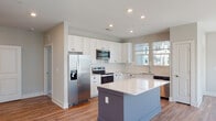 Located at 1100 Hampton Rivers Rd in Charleston, SC, this single-floor home offers a thoughtfully designed open-concept layout with modern finishes throughout. The kitchen is a standout feature, outfitted with crisp white shaker cabinetry, gleaming white quartz countertops, a full suite of stainless steel appliances including a French door refrigerator, electric range, over-the-range microwave, and dishwasher. A two-toned center island provides additional prep space and storage. Hardwood-style flooring runs through the main living areas, complementing the neutral color palette. The expansive living area is bathed in natural light from a bank of large windows and is equipped with a ceiling fan overhead. Bedrooms feature plush carpeting and generous closet space, including a walk-in closet with wire shelving. The bathrooms are finished with wood-look flooring, a tub-shower combo, and a dual-sink vanity with a large mirror in the primary bath. A dedicated laundry room houses a full-size top-loading washer and dryer. Clean lines, recessed lighting, and a bright, airy ambiance define this well-appointed Charleston home.