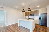 Located at 4660 Derrick Rd in Union City, GA, this well-appointed 2-bedroom, 2-bathroom single-story home offers a thoughtfully designed open-concept layout filled with modern finishes. The heart of the home is the combined kitchen, dining, and living area, where light wood-tone flooring flows seamlessly underfoot. The contemporary kitchen is a standout feature, boasting a large quartz waterfall island with an integrated sink, warm wood upper cabinetry contrasted by crisp lower cabinets, a marble-style tile backsplash, stainless steel appliances, and striking bronze pendant lighting that adds a refined touch. The open living area is bright and airy, with large windows inviting natural light and a ceiling fan overhead. Both bedrooms are carpeted for comfort, with the generously sized primary bedroom featuring a ceiling fan, natural light from a large window, and access to a well-organized walk-in closet complete with built-in shelving and drawers. The primary bathroom is sleekly designed with wood-tone cabinetry, a glass-enclosed walk-in shower with a rain showerhead, and durable hardwood-style flooring. Additional spaces include hallways, a dedicated laundry area, a utility room, and ample closet storage throughout, rounding out this move-in-ready home.