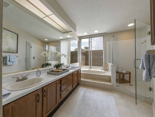 Primary bathroom with double-vanity, walk-in shower, and whirlpool tub - Golf Brook Apartments