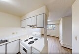 Located at 10500 45 Avenue NW in Edmonton, Alberta, this two-storey, 2-bedroom, 1-bathroom home offers a practical and comfortable layout spread across two floors. The main floor houses the primary living areas, including a bright living room with large sliding windows that frame views of surrounding trees and fill the space with natural light. A dedicated dining area sits adjacent to the kitchen, which features white cabinetry, a coil-element electric range, an under-cabinet range hood, a tile backsplash, and a peninsula counter with a built-in sink — ideal for casual meal prep. Light hardwood-style flooring runs throughout, complementing the neutral warm-toned walls and textured ceilings. A private patio extends the living space outdoors. The upper floor is home to two well-proportioned bedrooms, each with windows offering outdoor views and baseboard heating. The primary bedroom includes generous closet space with classic wood-toned bifold doors. Additional closets are distributed throughout the home, providing ample storage. The full bathroom features a tiled soaker tub and shower combination. Two staircases and two hallways ensure easy navigation between floors. Altogether, this home offers a clean, functional layout well-suited to everyday living.