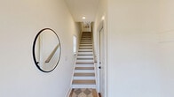 Located at 4248 Mora Meadow Ln in Charlotte, NC, this contemporary multi-story home offers a well-organized layout spread across four floors, blending modern design with practical functionality. The ground level includes a spacious garage with an automatic opener and utility area, providing convenient entry into the home. The main living floor features an inviting entrance hall with light wood flooring and a round mirror that sets a welcoming tone. The open-concept living and dining area is bright and airy, with recessed lighting, light hardwood floors, and a neutral palette. The kitchen is a standout, showcasing white shaker cabinetry, sleek quartz countertops, stainless steel appliances, a matte black faucet, and striking pendant lights with gold interiors. A dedicated office on the upper floors offers natural light through wide windows and a ceiling fan, ideal for remote work. The bathrooms feature white quartz vanities, light wood-look flooring, and matte black hardware for a cohesive modern aesthetic. Both bedrooms are well-sized and serene, including a comfortable primary suite. A private balcony provides outdoor views of the surrounding Charlotte streetscape and green space. With four staircases, a laundry room, and ample closet storage throughout, this home delivers efficient, thoughtfully designed urban living.