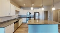 Located at 3109 Market Ln in Kenosha, Wisconsin, this single-floor residence offers a thoughtfully designed layout with modern finishes throughout. The kitchen serves as the centerpiece of the home, showcasing crisp white shaker-style cabinetry, granite countertops, and a full suite of stainless steel appliances including a refrigerator, electric range, over-the-range microwave, and dishwasher. A central island with a granite top provides additional workspace and casual seating, while pendant lighting overhead adds a polished touch. Wood-look flooring runs throughout the main living and kitchen areas, lending a warm, cohesive feel to the open-concept space. The bedrooms feature soft carpeting, ceiling fans, and windows with blinds that allow natural light to filter in. Each bedroom also includes closet access, offering practical storage. The bathroom is finished with tile-look flooring, a granite-topped vanity with white cabinetry, a large mirror, and a full tub-shower combination. Neutral wall tones and recessed lighting throughout the home create a clean, inviting ambiance that is both functional and comfortable. This residence combines contemporary design elements with practical amenities to deliver a well-rounded living experience.