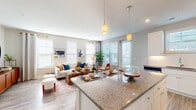 This well-appointed single-floor residence offers a thoughtfully designed open-concept layout that seamlessly connects the kitchen, dining, and living areas. The kitchen is a standout feature, showcasing white shaker cabinetry, granite countertops, a classic subway tile backsplash, stainless steel appliances, and a large island with pendant lighting and bar seating — ideal for both cooking and casual dining. Wood-look luxury vinyl plank flooring runs throughout the main living spaces, adding warmth and durability.

The living room is generously sized and bathed in natural light from multiple windows fitted with blinds and decorative curtains. Recessed lighting complements the bright, neutral palette, creating an inviting and airy atmosphere throughout.

The bedroom is a comfortable retreat, featuring plush carpet, a ceiling fan, and ample natural light. It connects directly to a well-proportioned en-suite bathroom with granite countertops, white cabinetry, wood-look flooring, and access to a spacious walk-in closet with multi-tier wire shelving. A central hallway links all areas of the home efficiently, with additional storage and easy access to all rooms. The overall design is clean, modern, and move-in ready.
