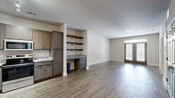 Located at 100 Comet Creek Lane in Goose Creek, SC, this well-appointed 2-bedroom, 2-bathroom single-story home offers a thoughtfully designed layout with a clean, modern aesthetic throughout. The open-concept kitchen and living area forms the heart of the home, featuring wood-look plank flooring, gray-toned cabinetry with granite countertops, stainless steel appliances, and track lighting overhead. A built-in desk nook with open shelving and additional drawer storage provides a functional workspace that flows seamlessly into the living area, which opens to the exterior via a glass door. The spacious primary bedroom is carpeted and bathed in natural light from dual windows, and includes a ceiling fan and a walk-in closet outfitted with wire shelving. The second bedroom also features wood-look flooring, neutral tones, and natural light. Both bathrooms are finished with dark cabinetry, granite-topped vanities, and wood-look tile flooring; one bathroom includes a tub-shower combination with built-in shelving and additional wire-rack storage. The home also includes two closets for ample storage. Neutral wall tones and consistent finishes throughout the home create a cohesive, move-in-ready atmosphere.