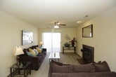 This single-story residence offers a well-organized layout with a variety of functional spaces throughout. The living room serves as the central gathering area, anchored by a wood-burning fireplace framed in terra cotta tile with a raised hearth. A decorative mirror hangs above the mantle, and a ceiling fan provides year-round comfort. Sliding glass doors allow natural light to fill the space, which features neutral carpet and a textured ceiling consistent throughout the home.

The galley-style kitchen is efficiently designed with warm oak cabinetry extending to the ceiling, ample counter space, a double sink, and a full suite of white appliances including a refrigerator, electric range, microwave, and dishwasher. Tile flooring adds durability underfoot.

Multiple bedrooms are present, each finished with plush carpet, ceiling fans, and windows with blinds. The primary bedroom includes a mirrored sliding-door closet. Additional bedrooms are similarly appointed, offering comfortable and flexible sleeping arrangements.

The bathrooms feature tile flooring and shower-tub combinations. One bathroom conveniently houses in-unit washer and dryer hookups with built-in shelving, adding notable practicality to the space.