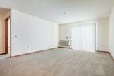 Located at 2800 Mickelson Pkwy in Fitchburg, Wisconsin, this one-bedroom, two-bathroom residence offers a practical and comfortable single-floor layout. The open-concept living and dining area is finished with plush wall-to-wall carpeting and features a sliding glass door fitted with vertical blinds, allowing natural light to fill the space. A wall-mounted HVAC unit provides climate control in the living area.

The kitchen is well-appointed with warm oak cabinetry, granite-style countertops, and hardwood-style flooring. Black appliances — including a refrigerator, dishwasher, and range — are complemented by a peninsula that separates the kitchen from the living space, ideal for casual dining or meal prep.

The bedroom is a comfortable size, featuring a ceiling fan, baseboard heating, and two windows that bring in generous natural light. Three closets throughout the unit provide ample storage.

The bathrooms include a full bath with an oak vanity, medicine cabinet, and a well-lit mirror. A notable convenience is the in-unit washer located adjacent to the bathroom. Warm wood-tone doors and trim carry throughout, giving the space a cohesive, welcoming aesthetic. Textured ceilings and wood-toned accents add to the unit's classic residential character.