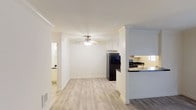 Located at 924 Encinitas Blvd in Encinitas, this single-story unit offers a clean, functional layout with a bright and neutral aesthetic throughout. The living area features light-toned hard flooring, crisp white walls, and crown molding accents, with a ceiling fan overhead adding both style and practicality. A sliding glass door leads to an outdoor area, allowing natural light to fill the space. The semi-open kitchen is separated from the living area by a partial wall with a breakfast bar counter finished in dark granite. The kitchen itself is well-equipped, featuring white cabinetry extending to the ceiling, dark granite countertops, a stainless steel sink, black appliances including a gas range and refrigerator, and light hard flooring. A window provides natural light and ventilation. The bedrooms are carpeted and feature ceiling fans, natural light from windows with blinds, and generous floor space. Both bathrooms are finished in clean white tones, each equipped with a tiled shower-tub combination and chrome fixtures. The entry area also features hard flooring, contributing to the cohesive, low-maintenance character of the unit.