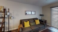 Located at 600 Front Street in San Diego, this single-floor unit offers a well-organized layout designed for comfortable everyday living. Dark hardwood-style flooring runs consistently throughout the space, creating a cohesive and warm aesthetic from entry to living area.

A long, clean-lined hallway with neutral-toned walls and crisp white baseboards serves as the main corridor, connecting the various areas of the unit. The hallway opens into a living room featuring neutral walls, natural light filtered through horizontal blinds, and ample wall space.

The kitchen is thoughtfully appointed with white cabinetry, granite-style countertops, a double stainless steel sink, and a full suite of stainless steel appliances including a range, over-the-range microwave, and refrigerator. Track lighting above provides functional illumination, while a breakfast bar offers additional prep or dining space.

The bedroom is a comfortable, quiet retreat with a window fitted with layered blinds, neutral walls, and continued dark hardwood-style flooring. A mirrored sliding closet door adds depth to the room.

The bathroom includes a full tub-shower combination, white cabinetry with an integrated sink, and a decorative framed mirror with vanity lighting above, completing the unit's clean, functional design.
