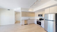 Located at 1715 N Dixie Hwy in Lake Worth Beach, Florida, this modern 3-bedroom, 2-bathroom residence offers a thoughtfully designed single-floor layout with clean, contemporary finishes throughout. Light wood-tone flooring flows seamlessly across all rooms, complementing the bright, neutral color palette that gives the space an airy and welcoming ambiance.

The open-concept kitchen, dining, and living area serves as the heart of the home. The kitchen features stainless steel appliances — including a range, microwave, and dishwasher — paired with light wood upper cabinetry, white lower cabinets, and crisp white countertops. Track lighting overhead provides excellent illumination. An adjacent pantry adds practical storage.

The primary bedroom is a well-proportioned retreat with access to an en-suite bathroom boasting dual sinks, a white floating vanity, and a separate shower. A second full bathroom includes a soaking tub with tiled surround and a floating vanity. Two additional bedrooms are bright and airy, each featuring large windows with scenic outdoor views of the surrounding Lake Worth Beach landscape.

Further highlights include a dedicated laundry area, six closets providing ample storage, a balcony for outdoor enjoyment, and a welcoming entrance. The overall design is clean and modern, ideal for comfortable Florida living.