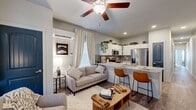 Located in Colorado Springs, CO, this 2-bedroom, 2-bathroom single-floor home offers a thoughtfully designed layout that maximizes every inch of its comfortable footprint. The open-concept living and kitchen area serves as the heart of the home, where wood-look flooring, a ceiling fan, and large windows draped in neutral linen curtains create a bright, welcoming atmosphere. The kitchen stands out with striking granite countertops, white cabinetry, a tile backsplash, and stainless steel appliances, including a French door refrigerator. A peninsula with bar seating connects the kitchen seamlessly to the living space. The living room offers generous natural light through multiple windows and features a wall-mounted TV area. Bold teal-painted interior doors add a distinctive design touch throughout the home. The primary bedroom is a comfortable retreat with plush carpeting, a built-in closet with stylish arched double doors, and an en-suite bathroom featuring granite countertops. The second bedroom also features carpet flooring and direct bathroom access. Both bathrooms are finished with warm wood-look tile flooring and clean, neutral palettes. A mini-split system provides efficient climate control throughout the home.
