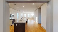 This single-floor space in Huntsville, Alabama, offers a thoughtfully designed open-concept layout that connects the kitchen and living area seamlessly. The kitchen serves as a central hub, anchored by a large island with a dark base and light granite countertop, complete with an undermount sink. Ample cabinetry in a soft gray-white finish lines the walls, complemented by a full suite of stainless steel appliances, including a gas range, built-in microwave, and French door refrigerator. A subway tile backsplash adds a clean, modern touch.

Light hardwood flooring extends throughout the entire space, creating a warm and cohesive aesthetic. Recessed lighting illuminates the open living area, which benefits from multiple windows that invite natural light. The bedrooms are bright and well-proportioned, each featuring hardwood floors, ceiling fans, and windows with blinds. The bathroom is finished with matching granite countertops, gray shaker-style cabinetry, a framed mirror, and a glass-enclosed shower, maintaining the modern design language found throughout the rest of the space.