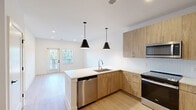 Located at 1030–1032 Union St in Spartanburg, SC, this thoughtfully designed one-bedroom, one-bathroom unit offers a clean, modern aesthetic throughout its single floor. Light wood-tone luxury vinyl plank flooring flows seamlessly across the living spaces, complementing the crisp white walls and recessed lighting that keep the interior bright and welcoming.

The kitchen is a standout feature, showcasing warm wood-grain cabinetry, white quartz countertops, a herringbone tile backsplash, and a full suite of stainless steel appliances including a refrigerator with ice maker, range, microwave, and dishwasher. Striking matte black cone pendant lights hang above the peninsula, adding a contemporary design touch.

The spacious bedroom receives natural light through a window with blinds, and includes a ceiling fan for comfort. Three closets provide generous storage, one of which features wire shelving systems for efficient organization. A dedicated laundry area adds everyday convenience.

The bathroom is finished with a wood-toned vanity, white quartz countertop, a framed black mirror, and stylish globe vanity lighting above, with light tile flooring tying the space together. A private patio with a glass door brings in outdoor light and offers a seamless indoor-outdoor connection. The unit's clean, contemporary design makes it a highly functional and visually cohesive living space.