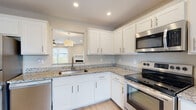 Located at 3884 N Chalet Cir in Beavercreek, Ohio, this two-story home offers a well-designed layout with modern finishes throughout. The kitchen is a standout feature, showcasing crisp white shaker-style cabinetry, granite countertops, light hardwood-style flooring, and a full suite of stainless steel appliances including a refrigerator, electric range, microwave, and dishwasher. A pass-through opening connects the kitchen to the adjacent living area, enhancing the open feel of the main level. The living room is bright and inviting, with light hardwood-style flooring, recessed lighting, a ceiling fan, a fireplace with a white mantel, and sliding glass doors that bring in abundant natural light and provide outdoor access. Bathrooms are finished with neutral tones, granite vanity tops, and light flooring, offering a clean and functional design. Bedrooms feature plush carpeting, ceiling fans, and generous closet space with wire shelving systems. Vaulted ceilings in select rooms add to the sense of openness. A dedicated laundry area houses a full-size washer and dryer. The home's warm, neutral color palette and thoughtful layout create a comfortable and cohesive living environment across both floors.