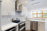 Located at 3555 Georgia Ave NW in Washington, DC, this thoughtfully designed one-bedroom, one-bathroom residence offers a bright and modern living experience across a single floor. The open-concept kitchen and living area serves as the heart of the home, anchored by a dramatic wall of wood-framed, floor-to-ceiling windows that flood the space with natural light and frame lush tree-lined views of the neighborhood. Light-toned hardwood flooring and soft gray walls create a clean, contemporary aesthetic throughout.

The kitchen is well-appointed with white shaker cabinetry, sleek quartz countertops, a geometric herringbone tile backsplash, and a full suite of stainless steel appliances including a French door refrigerator, electric range, built-in microwave, and dishwasher. A pendant light fixture above the peninsula adds a stylish focal point.

The bedroom is a comfortable, well-lit retreat, benefiting from its own large wood-framed windows with treetop and street views, and the same warm hardwood flooring found throughout the unit.

The bathroom is a standout feature, showcasing floor-to-ceiling marble-look porcelain tile in the walk-in shower, complete with a rainfall showerhead, handheld fixture, and a recessed niche. White cabinetry and bright finishes complete the refined look.