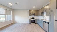 Located on Eastwood Road SE in Rochester, Minnesota, this single-floor, one-bedroom, one-bathroom unit offers a clean and modern living experience. The open-concept kitchen and living area is finished with light wood-look luxury vinyl plank flooring, recessed lighting, and neutral-toned walls that create a bright, welcoming atmosphere. The kitchen is equipped with stainless steel appliances — including a range, microwave, refrigerator, and dishwasher — complemented by two-tone cabinetry in taupe and gray, stone-look countertops, and a classic white subway tile backsplash. A window in the living area allows natural light to fill the space. The bedroom features plush wall-to-wall carpeting, a large window overlooking the surrounding neighborhood, and a generous double-door closet for ample storage. The full bathroom includes a soaking tub and shower combination finished in crisp white, with brushed gold fixtures that add a touch of warmth. A hallway connects the living areas to the private quarters, with additional closets and a utility room providing practical storage solutions. The overall design balances contemporary finishes with functional layouts, making this a comfortable and efficient home.