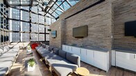 The Drakestone is a striking rooftop lounge that masterfully blends indoor and outdoor living through an expansive glass curtain wall and skylight ceiling system. Floor-to-ceiling steel-framed windows and a fully glazed roof flood the interior with abundant natural light throughout the day, while framing sweeping panoramic views of the surrounding cityscape. The architectural design balances industrial and modern aesthetics, pairing warm-toned horizontal-stack brick accent walls with light hardwood flooring that runs throughout the space. Multiple flat-screen televisions are mounted along the brick feature wall, supported by sleek white cabinetry and a built-in beverage refrigerator, making the lounge well-equipped for both casual gatherings and curated events. The seating arrangement features generous runs of modular grey upholstered sofas and low-profile lounge chairs positioned along the glass perimeter, punctuated by slim metal coffee tables adorned with potted succulents and greenery. A bold red accent chair adds a pop of color near the entrance. A branded entry mat bearing "The Drakestone" name greets visitors at the glass door entry, which opens directly to a rooftop terrace, further extending the entertaining possibilities. The overall ambiance is bright, airy, and sophisticated.