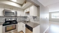 Located at 555 Church Street in the heart of Nashville, Tennessee, this 2-bedroom, 1-bathroom residence offers a thoughtfully designed layout across a single floor. Light wood-tone flooring flows consistently throughout the space, complementing neutral gray walls and white trim for a clean, contemporary aesthetic.

The kitchen is a standout feature, outfitted with white shaker-style cabinetry, sleek gray countertops, and a striking marble-patterned tile backsplash. Stainless steel appliances — including a range, over-the-range microwave, refrigerator, and dishwasher — complete the functional and stylish cooking space.

The primary bedroom is generously proportioned and includes a dedicated closet, while the second bedroom offers a comfortable, versatile space. Both rooms benefit from natural light through windows that frame views of the Nashville skyline. Track lighting in the primary bedroom adds an additional design element.

The full bathroom features a tub-shower combination with clean white surround, a toilet, and a vanity with matching gray countertops, maintaining the home's consistent modern palette.

A hallway connects all rooms efficiently, and the textured ceilings are present throughout. The overall ambiance is bright, clean, and move-in ready, making this an ideal urban Nashville residence.