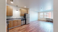 Located at 1440 Independence St in Lakewood, Colorado, this one-bedroom, one-bathroom unit offers a well-designed layout with a cohesive modern aesthetic. Warm hardwood-style flooring runs throughout the entire space, creating a consistent and inviting feel from room to room. The combined kitchen and living area serves as the heart of the unit, where a fully equipped kitchen stands out with light wood cabinetry, a green glass tile backsplash, stainless steel appliances including a range, microwave, dishwasher, and refrigerator, and a pendant light over the sink. A bold green entry door adds a pop of color and contemporary character to the space. The bedroom is a comfortable, well-proportioned room filled with natural light from a large window that offers views of the surrounding Lakewood neighborhood, and includes a dedicated closet for storage. The bathroom features a full tub-shower combination with chrome fixtures, clean white finishes, and matching hardwood-style flooring that ties it seamlessly to the rest of the unit. Recessed lighting throughout provides even, functional illumination, while neutral white walls offer a bright, versatile canvas. This unit combines practical functionality with a clean, modern design sensibility.