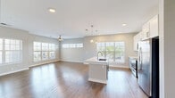 Located at 3010 Furr Court in Charlotte, NC, this thoughtfully designed 2-bedroom, 2-bathroom home offers a comfortable and modern living experience across a single floor. The open-concept layout seamlessly connects the living room, dining area, and kitchen, creating a bright and airy communal space. Large windows with plantation-style blinds and transom windows above flood the area with natural light, while wood-look flooring and neutral gray tones give the space a clean, contemporary feel. A ceiling fan adds comfort to the living area.

The kitchen is a standout feature, centered around a large white island with a built-in sink and pendant lighting overhead. White cabinetry, a classic tile backsplash, and stainless steel appliances — including a refrigerator, microwave, and range — complete the space.

Both bedrooms are generously sized with plush carpeting, ceiling fans, and windows that bring in ample daylight. The spacious primary bedroom includes access to a walk-in closet outfitted with wire shelving. The second bedroom also features a closet for additional storage. Two full bathrooms serve the home, one featuring a tub-shower combination. Additional highlights include a dedicated laundry area, a utility room, an entrance foyer, and a private balcony.