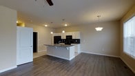 This thoughtfully designed multi-floor space spans three levels, offering a versatile and functional layout with modern finishes throughout. The open-concept main living area serves as the heart of the home, seamlessly connecting the kitchen and living spaces for an airy, cohesive feel. The kitchen is a standout feature, showcasing crisp white cabinetry, dark granite countertops, and a central island with bar seating — ideal for casual dining or entertaining. Black appliances, including a refrigerator, oven, and built-in microwave, complement the space's contemporary aesthetic, while a classic tile backsplash adds a refined finishing touch. Pendant lighting hangs above the island, providing both task illumination and decorative flair, alongside a ceiling fan that contributes to the room's comfort. Rich, dark hardwood-style flooring runs throughout the main level, grounding the space with warmth and visual continuity. Neutral-toned walls create a clean, versatile backdrop that suits a variety of décor styles. The layout flows naturally between rooms, with multiple doorways indicating well-connected living areas across all three floors. Overall, the space presents a polished, move-in-ready environment with a modern sensibility and functional design at every turn.
