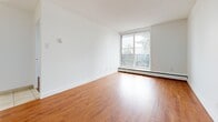 Located at 2920 Fairlea Crescent in Ottawa, Ontario, this two-bedroom, one-bathroom unit offers a practical and well-organized single-floor layout. The interior is finished with warm-toned hardwood flooring throughout the main living areas and bedrooms, complemented by crisp white walls and textured ceilings that create a clean, bright atmosphere.

The living room is a generous open space anchored by a large sliding window that invites abundant natural light and provides outdoor views of the surrounding neighbourhood. A pass-through opening connects the living area to the kitchen, offering a convenient and communicative layout. The kitchen is equipped with appliances and cabinetry visible through the pass-through.

Both bedrooms feature the same warm hardwood flooring and are served by large windows with baseboard heating beneath, ensuring comfort throughout the seasons. The primary bedroom includes a built-in sliding door closet for practical storage. Each bedroom benefits from good natural light.

The hallway, finished in light ceramic tile, connects all rooms efficiently and leads to the full bathroom. The bathroom is finished with white subway tile surrounding a full soaking tub, paired with chrome fixtures and clean white fittings throughout.

Overall, the unit presents a bright, neutral, and move-in ready environment suited for comfortable everyday living.